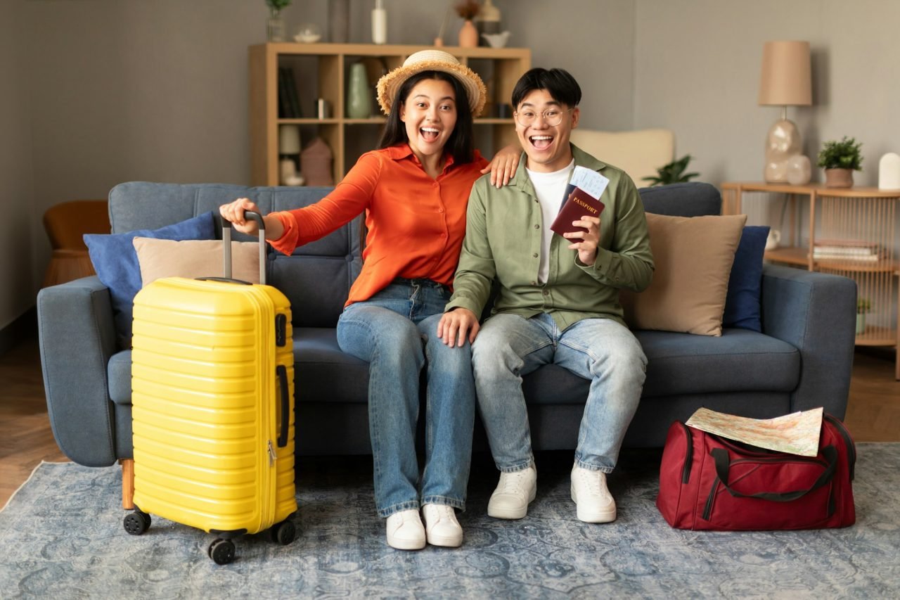 joyful japanese travelers couple posing with travel tickets at home